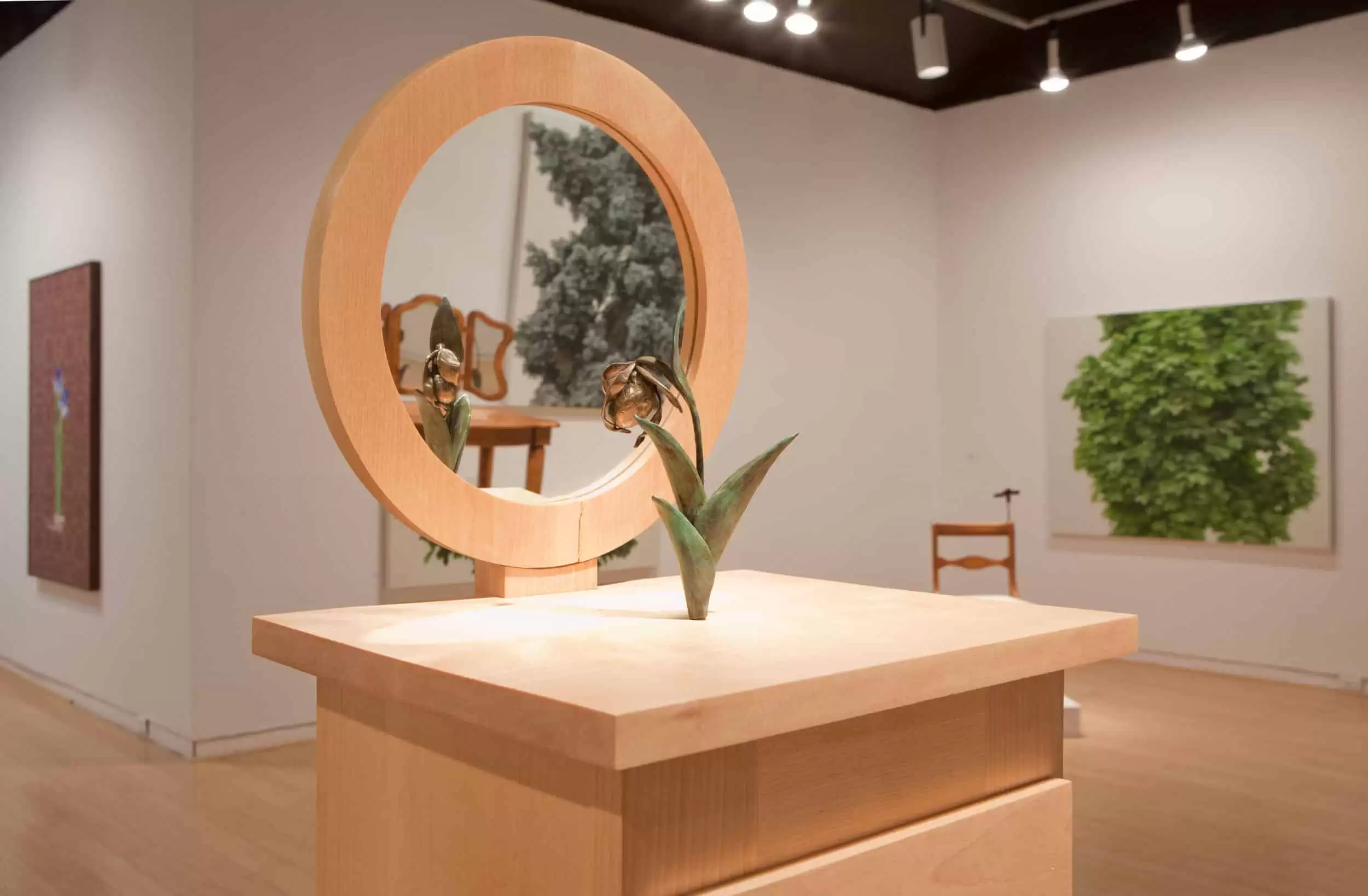 Gallery view of the exhibition Nature in Culture featuring a sculpture by Melissa Doherty installed in the AGP's main gallery. Droopy tulip sitting on a wooden table looking into a mirror.