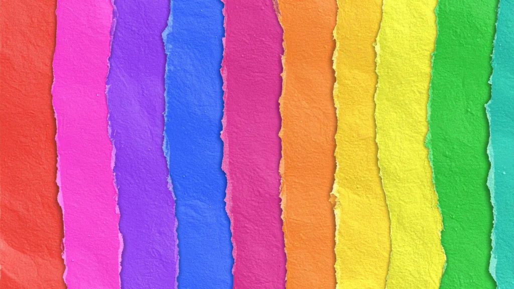 Ripped paper strips in vibrant colors—red, pink, purple, blue, orange, yellow, and green—are aligned vertically, creating a bold, textured rainbow pattern.