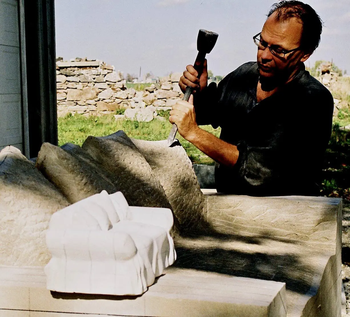 Ernest Daetwyler using model to carve limestone loveseat