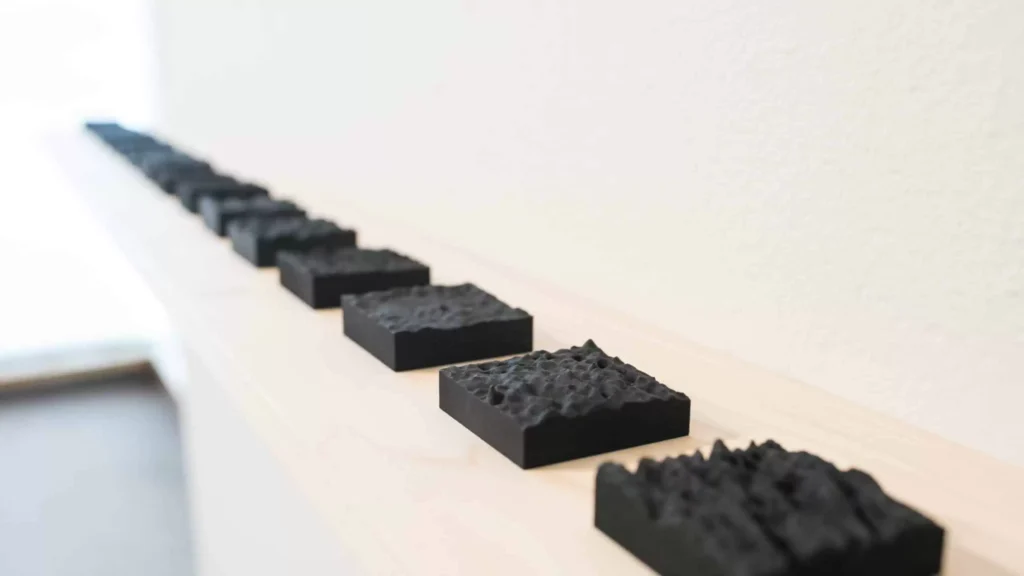 Gallery view of Sasha Opeiko's solo exhibition 217. Series of black 3-D printed textural surfaces on a wooden shelf installed on the AGP ramps.