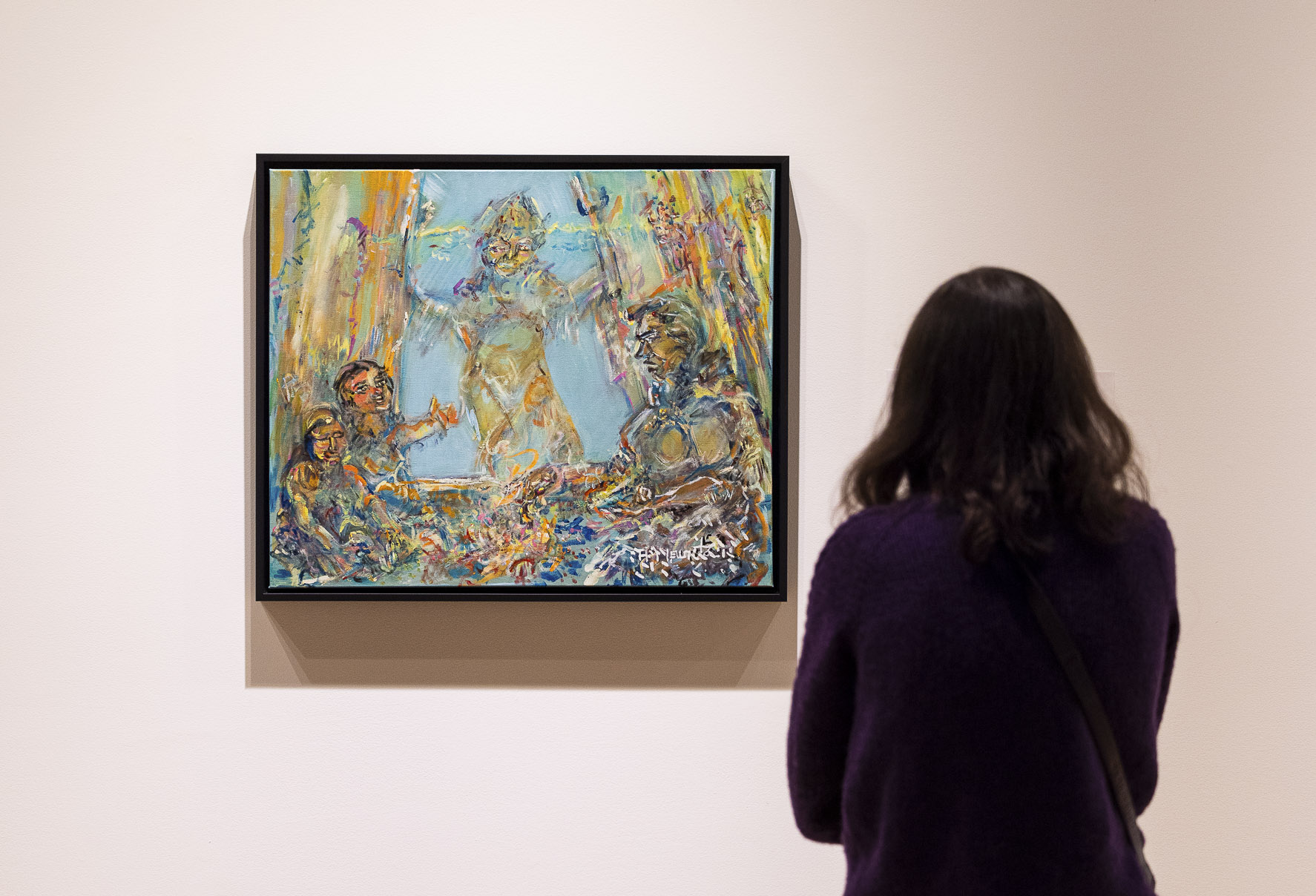 A person stands with their back to the camera facing a painting by artist Antoine Mountain in the gallery