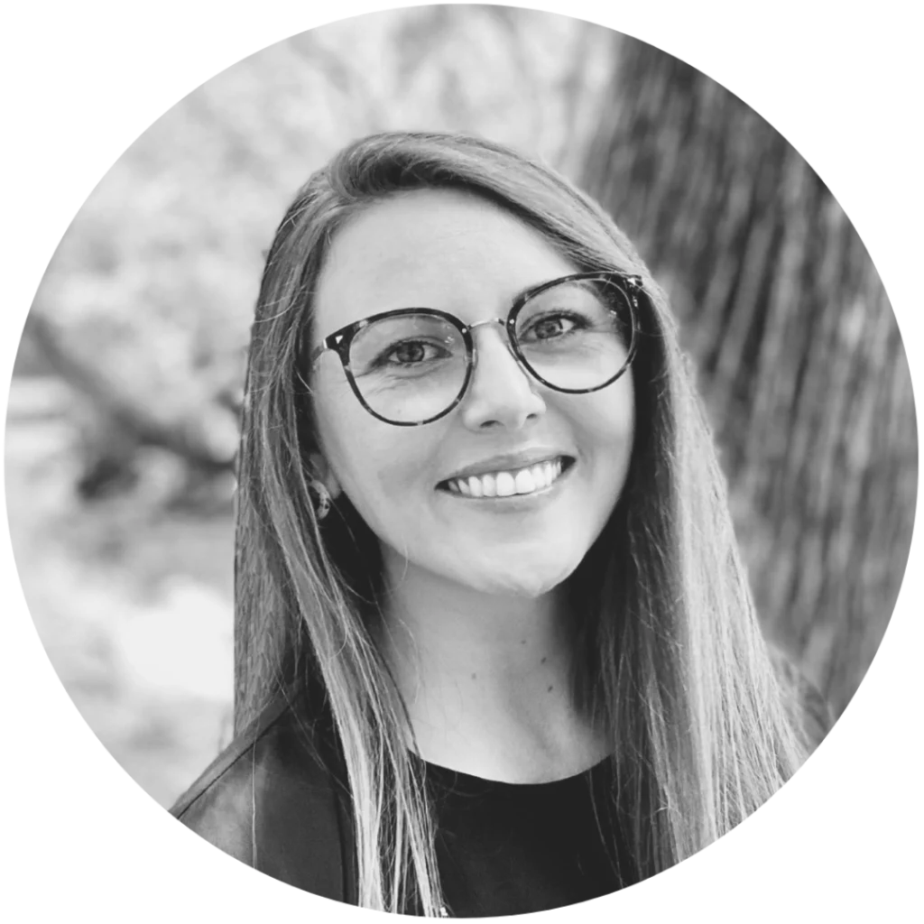 Headshot of Briar Sutherland. She smiles facing the camera. Her long hair is worn down framing her face and she wears glasses