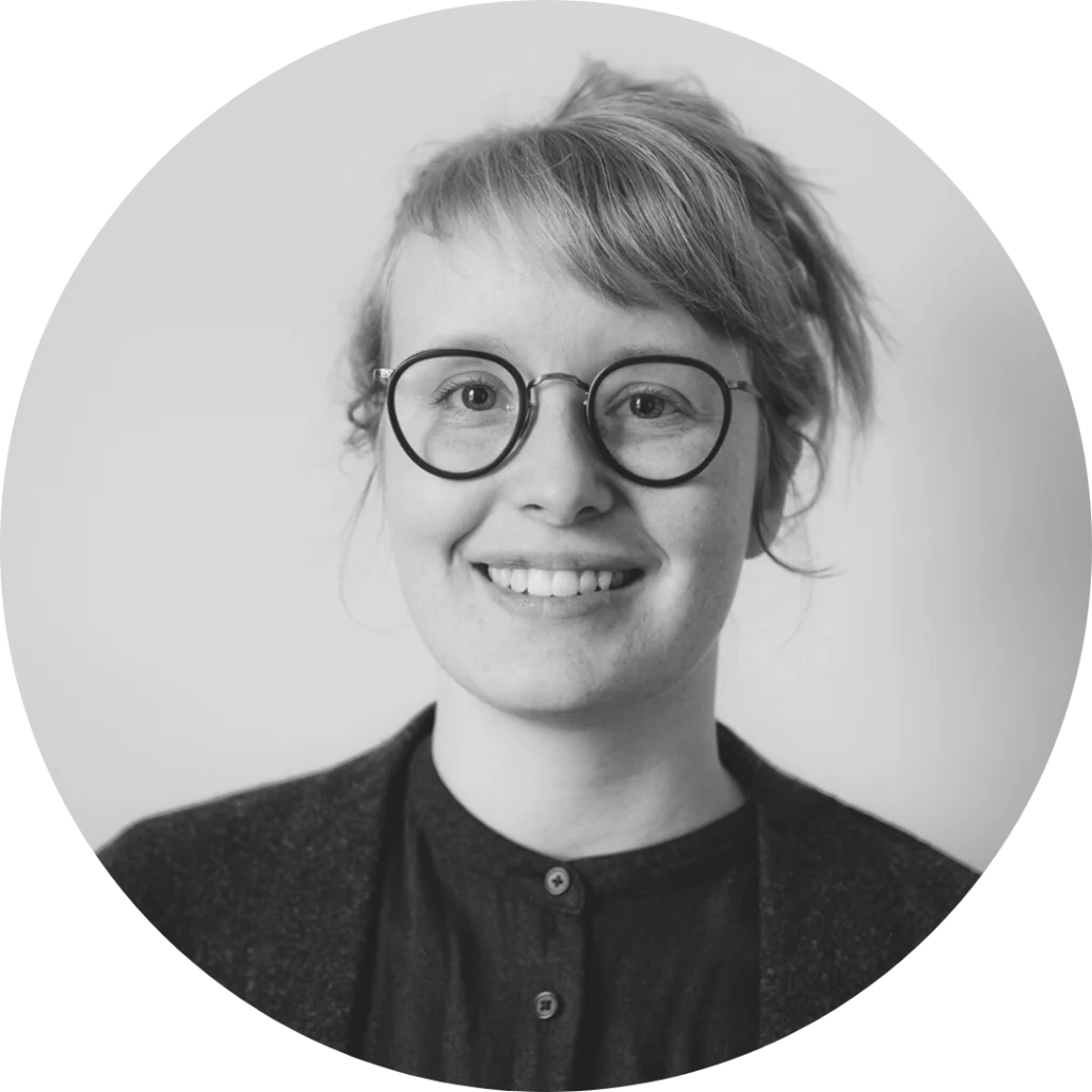 Headshot of Laura Thompson. Laura faces the camera and smiles. Her hair is pulled back and she wears glasses and a black shirt