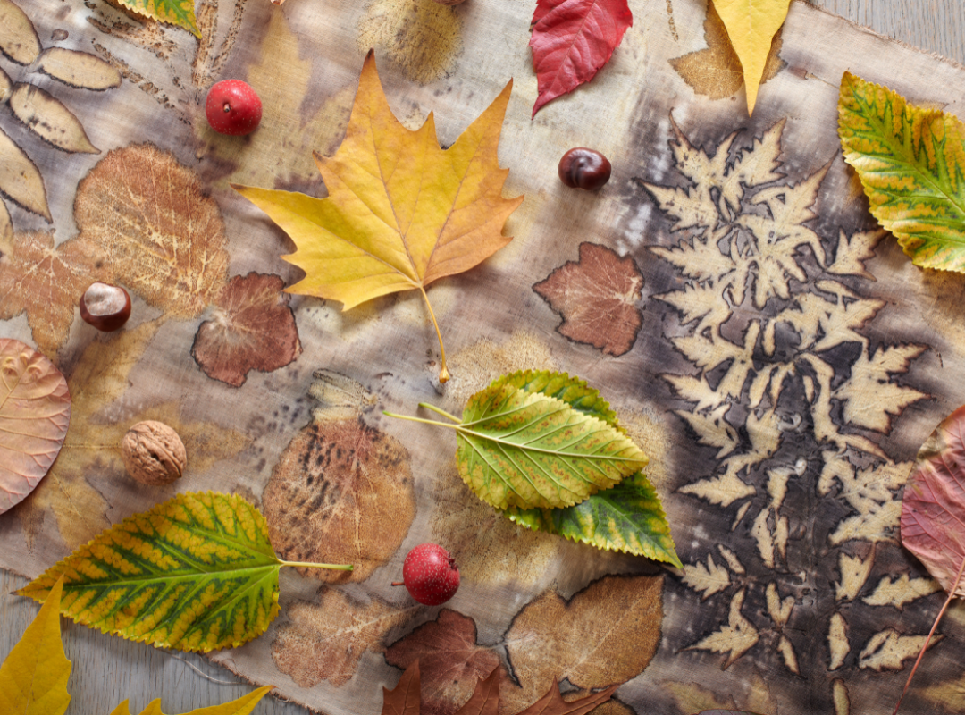 Leaves and other natural material scattered across a table with printmaking supplies