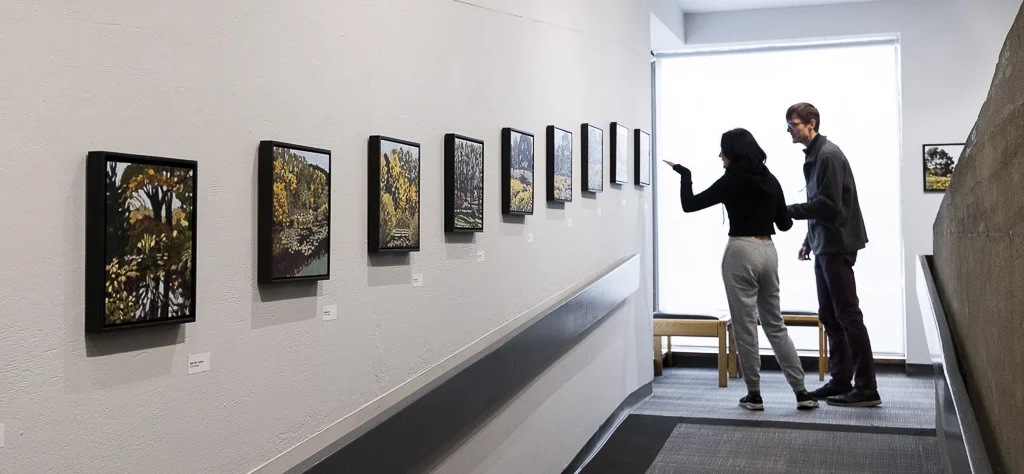 Two people viewing Laurie De Camillis' exhibition "Four Seasons" in the AGP Ramp Galleries