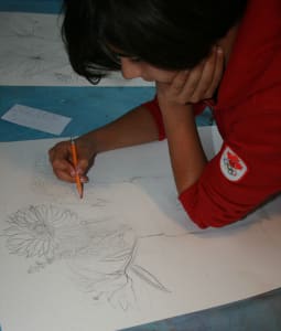 Child sketching a vase full of flowers during AGP's art club
