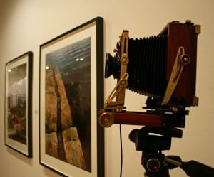 Arnold Zageris's vintage camera installed beside two framed photographs