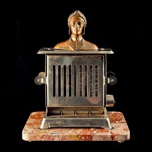Assemblage by Michael Poulton featuring a bronze cast portrait on a small metal heater.