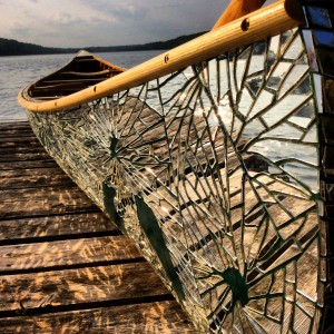 Sculpture by Brad Copping. Canoe made from multiple mirror pieces sitting on a dock.