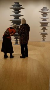 Two people viewing Lyn Carter's fabric skinned wood sculptures suspended in AGP's main gallery