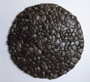 Wooden sculpture by Rod Mireau. Carved pine and walnut pieces that have been stained and charred installed as a circle on a white wall.