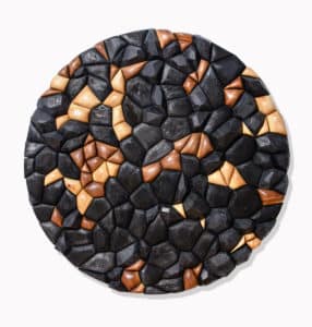 Wood sculpture by Rod Mireau. Circle made of carved wood pieces that have been stained and charred and installed on a white wall.