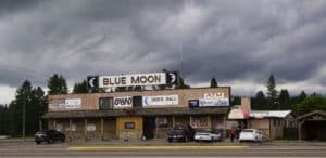 Photograph of a rural roadside Casino in Montana USA. Signs read: "Blue Moon," "Casino," Dance Hall," and "ATM."