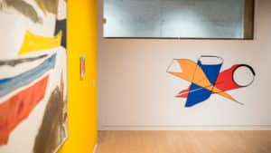 Digital drawing of yellow, blue, and red cylindrical shapes by Francisco-Fernando Granados installed as vinyl on the wall in AGP's main gallery