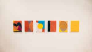 Six digital drawings by abstract artist Francisco-Fernando Granados installed as chromogenic prints mounted on plexiglass on the wall in AGP's main gallery. Digital drawings feature blocks of bright Yellow, orange, and blue with tick and thin curved lines.