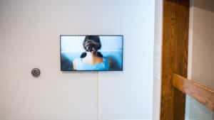 Gallery view of a tv installed on a white wall in the AGP ramps. TV features the back of a person sitting in a bathtub.
