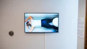 Gallery view of a tv installed on a white wall in the AGP ramps. TV features the a person laying face down on a bathroom floor.