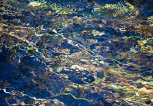 Photograph by Corin Ford Forrester of rippling water with blue, green, and yellow hues