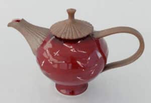 Red glazed porcelain teapot with brown bisque handle, spout, and lid by Bill Reddick