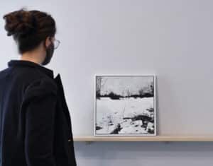 Person on the left looking at Shannon Taylor's ink and acrylic painting sitting on a wooden ledge installed on the AGP ramps