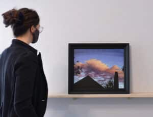 Person on left looking at an acrylic painting by Victoria Wallace sitting on a wooden ledge installed on the AGP ramps