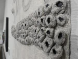 Detail photograph of Christianna Ferguson's wet felted fine merino silk & sumi ink. Series of textured white circles with black centres.