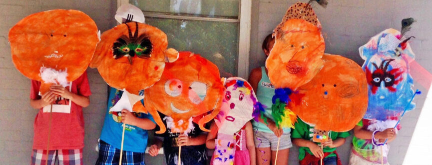 Seven children holding paper masks made during an AGP summer camp