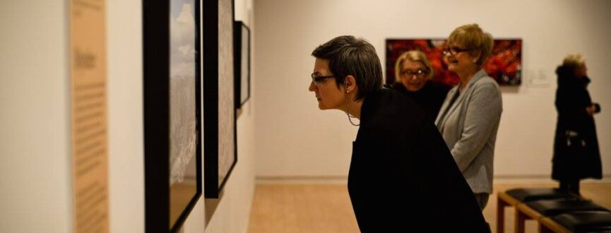 Four people looking at various artworks installed in AGP's main gallery
