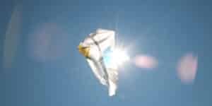 plastic bag floating in the sky, partially obscuring the sun. lens flares appear on a clear blue sky in the background