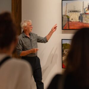Peer Christensen delivering an artist talk and pointing to one of his paintings on the wall