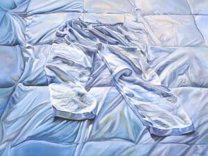 Painting of a pair of pants lying unworn on a quilted surface. Both the pants and the textile underneath are slightly wrinkled and painted in the same colour palette, so that it appears the pants blend in with the bedding