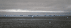 photograph of a flat iceberg floating in water by Arnold Zageris