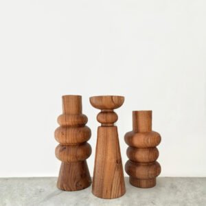 A group of three wood sculptures all with a flat top and bottom and curves.