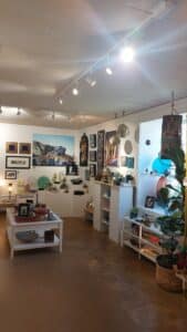 The interior of the artist's studio; works on display on shelving and on the walls.