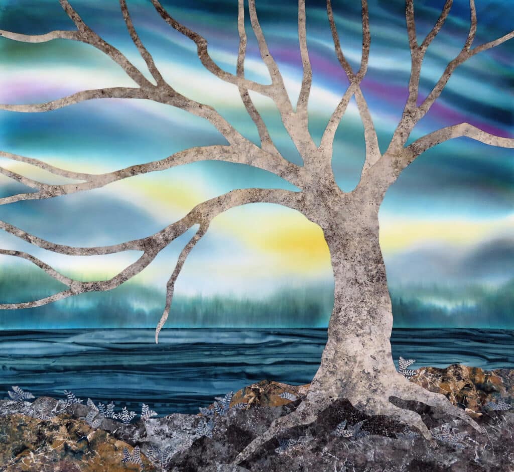 A landscape scene; a tree with many branches and no leaves sits on a rocky landscape on the water. The sky is yellow, green, and purple, like the Northern lights.